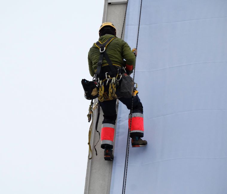 Rope access technician scales building facade for maintenance work.